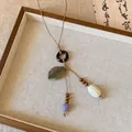 Détail du collier ethnique avec feuille de bronze, perles en bois et cordon tressé - Style Feuille de Bronze Café
