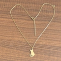 Gros plan d'un collier plaqué or 18 carats avec pendentif chat sur un fond en bois brun - Chat / Or