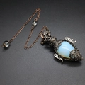 Macro shot of an opal gemstone pendant in a vintage copper filigree frame with pentagram - Opal + Pendulum Chain