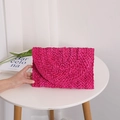 Fuchsia corn husk woven clutch bag with unique spiral texture on a white table - Rose Pink