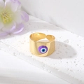 Gros plan détaillé d'une bague Evil Eye dorée avec émail violet sur surface texturée - Œil Violet