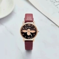 Detailed macro shot of a black dial featuring a golden bee motif and Roman numerals - Red