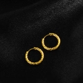 Macro shot of gold hoop earrings featuring a sophisticated quilted pattern on black silk - Quilted Pattern / Gold