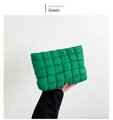 Détail d'une trousse matelassée verte tenue à la main montrant sa texture rembourrée - Vert