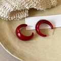 Detail view of deep red resin C-shape earrings on a ceramic plate with vintage vibes - Letter C-Shaped Resin Tie-Dye Hoops