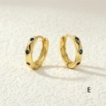 Macro detail of gold-plated hoop earrings featuring inlaid round blue cubic zirconia stones - Blue