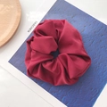 Detail of dark red satin scrunchie with soft pleats on a stylish magazine background - Burgundy