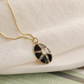 Macro detail of oval black enamel pendant with multi-color stones and golden chain - Gold Black Oval Cross Style