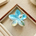 Blue plumeria hair claw clip with floral pattern in a wooden jewelry display tray - Blue Dandelion