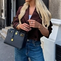 Chic black pebbled leather handbag with gold hardware paired with a brown buttoned coat - S / Burgundy