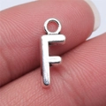 Silver alloy letter F alphabet pendant charm held on fingertip for size scale - Letter F (B15659) / Antique Silver