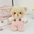 Dettaglio dell'orsetto di peluche bianco con salopette rosa e mini carrello della spesa - Rosa