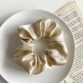 Elegant champagne gold satin scrunchie with silk texture on a white decorative plate - Cream White Small