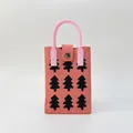 Detail of coral pink knitted phone bag with black pine patterns and round handle - Xmas Tree Pink
