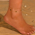 Double-layered gold titanium steel anklet with black Roman round disc on sandy beach - Black Shell Roman Numerals Anklet