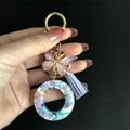 Close-up of resin keychain with gold butterfly charm, purple tassel and heart sequins - Letter O / Butterfly Tassel 8-Shape Buckle