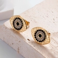 Goldene Evil Eye Ohrstecker mit schwarzen und klaren Kristallen auf Steinpodest - Teufelsauge Ohrstecker