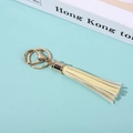 Fringed PU leather keychain with gold hardware on a blue background and prop book - Light Yellow