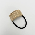 Detail eines mattgoldenen U-Haargummis mit Hammerschlag-Textur und schwarzem Gummiband - Sand Roségold Quadratisch