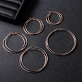Flat lay of five different sized rose gold hoop earrings on a black textured background - 5cm / Metallic Rose Gold