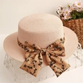 Detail of flat top straw boater hat with floral ribbon bow on white metal basket - Pink