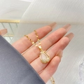 Collier tulipe doré élégant avec pierre œil-de-chat opale et zircons tenu à la main - Tulipe