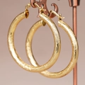 Orecchini a cerchio dorati lucidi con trame ondulate alternate e dettagli martellati fini - Oro