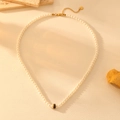 Detalle de collar de perlas blancas con cierre dorado y cuenta negra en cuero beige - Estilo de Circonita Negra (I610)
