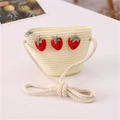 Detail of straw crossbody bag for girls featuring a red strawberry ornament and rope strap - Three Strawberries Style / Cream