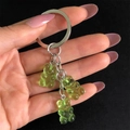 Close-up of green jelly resin bear charms on a metallic keyring held against a black backdrop - Green