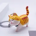 Close-up of cute yellow and white striped cat keychain with a black bow and metal ring - Yellow