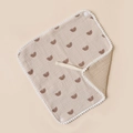 Detailed macro view of cotton baby bib with rainbow print and fluffy white pom-pom edges - Khaki And Khaki Rainbow