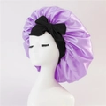 Purple satin sleep bonnet with a wide black bow tie on a white mannequin head - Medium Single Layer Black Cross Ribbon / Violet