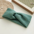 Detail of teal green knitted headband featuring thick wool texture and central twist knot - Green
