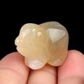 Mini hand-carved natural yellow agate pig figurine held between fingers for scale - Natural Agate