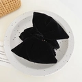 Detailed close-up of a large black velvet bow hair claw clip on a decorative tray - Velvet Bowknot / Black