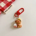 Detail of Capybara keychain with yellow headphones and red D-ring on beige background - Capybara - Listening to Music