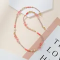 Macro detail of beaded eyewear chain with colorful resin beads and gold-tone metal spacers - Pink