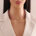 Pink and gold bead necklace with a natural pearl on a mannequin over a beige blazer - Pink