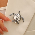 Vintage silver-tone turtle brooch with geometric shell texture on beige suit lapel - Antique Silver
