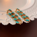 Detailed shot of golden chain earrings with turquoise enamel on a white ceramic plate - Gold Teal Enamel Chain Earrings