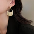Close-up of model wearing gold-plated oval fringe earrings with metallic tassels - Oval Ring Tassel / Gold