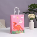 Rosa Papiertüte mit Dinosaurier-Motiv und weißen Kordelgriffen auf weißem Tisch - 21*15*8cm / Rosa Dinosaurier (Hey)