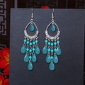 Macro shot of boho teardrop beaded fringe earrings with turquoise stones and silver accents - Cyan Blue Silver
