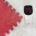 Pink plush EVA foam tile being tested for safety with an air quality monitor - Orange
