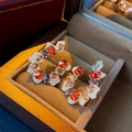 Macro-opname van gouden C-vormige oorbellen met gekleurde edelstenen in een juwelendoosje - Multicolor Oranje (Zilveren Naald)