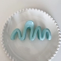 Light blue wave-shaped hair claw clip for thick hair displayed on white porcelain - Teal Blue