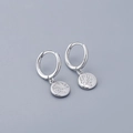 Macro shot of silver S925 sterling silver hoop earrings with vintage Indian head charms - Round Surface Earrings - Silver