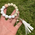 Detail of silicone beaded wristlet with sunflower print and leather tassel on grass - A-010/Gold White Leopard + White Tassel