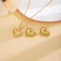 Detail view of heart-shaped golden necklace and earrings jewelry set on a pedestal - Gold Heart Style